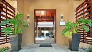 A hotel entrance with a wooden gate, potted plants, and a tiled floor. - Luxury Vacation Villa (Cape Town)
