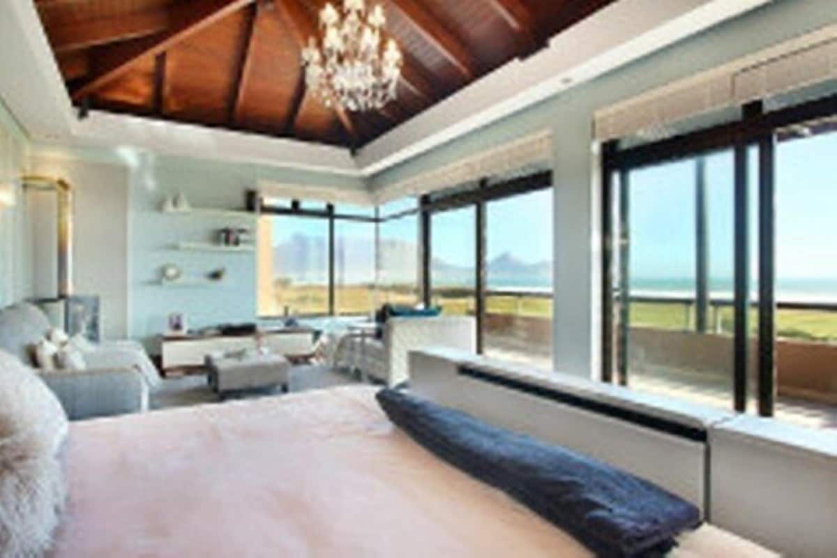 A spacious bedroom with a large bed, a chandelier, and a view of the ocean.