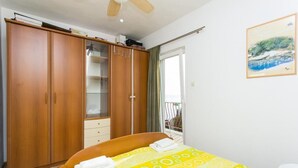 A bedroom with a bed, a wardrobe, a balcony with a view, and a ceiling fan. - Guest House Fontana - Two Bedroom Apartment with Balcony and Sea View (Mlini)
