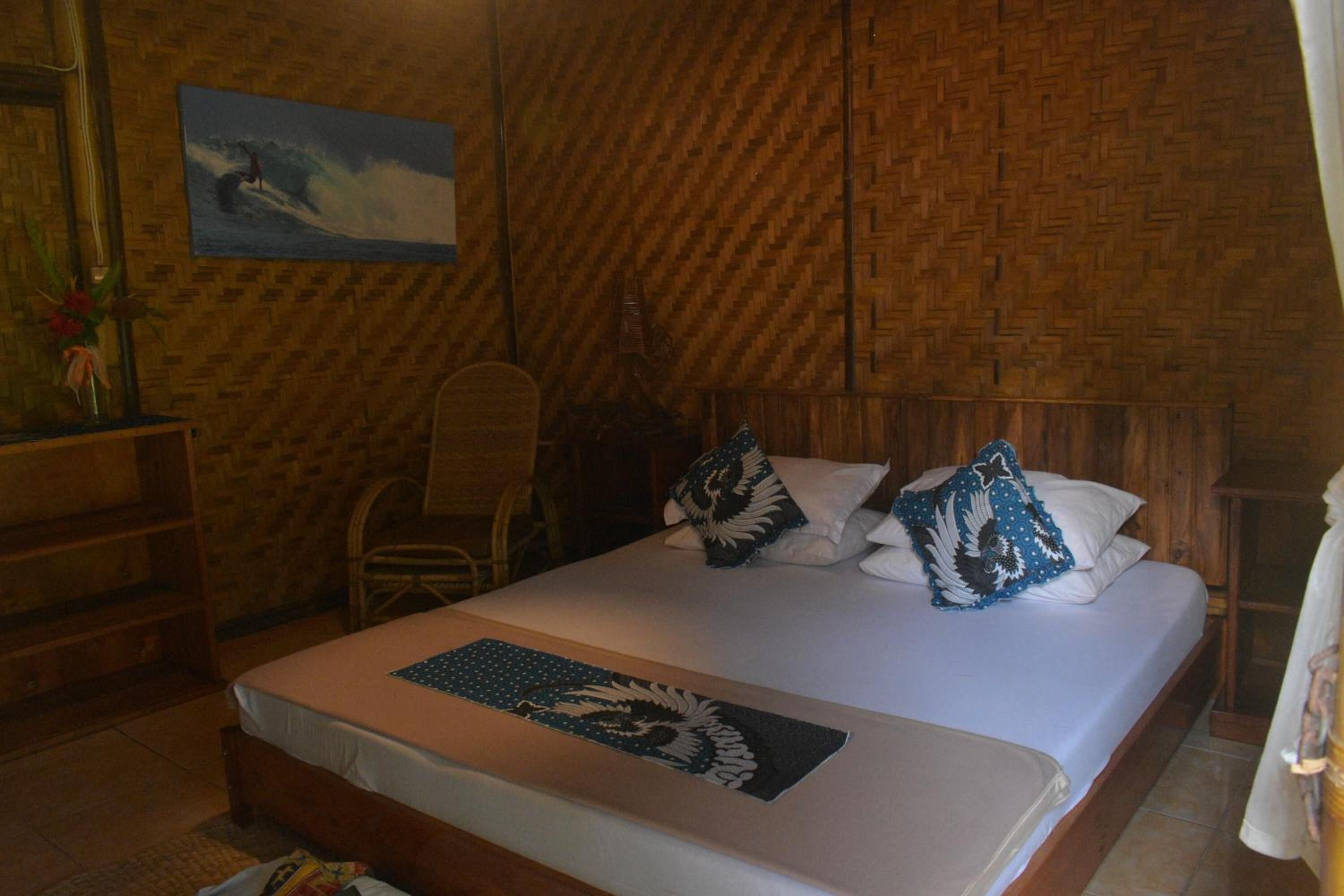 A room with a bed, a chair, a wooden wall, and a painting.
