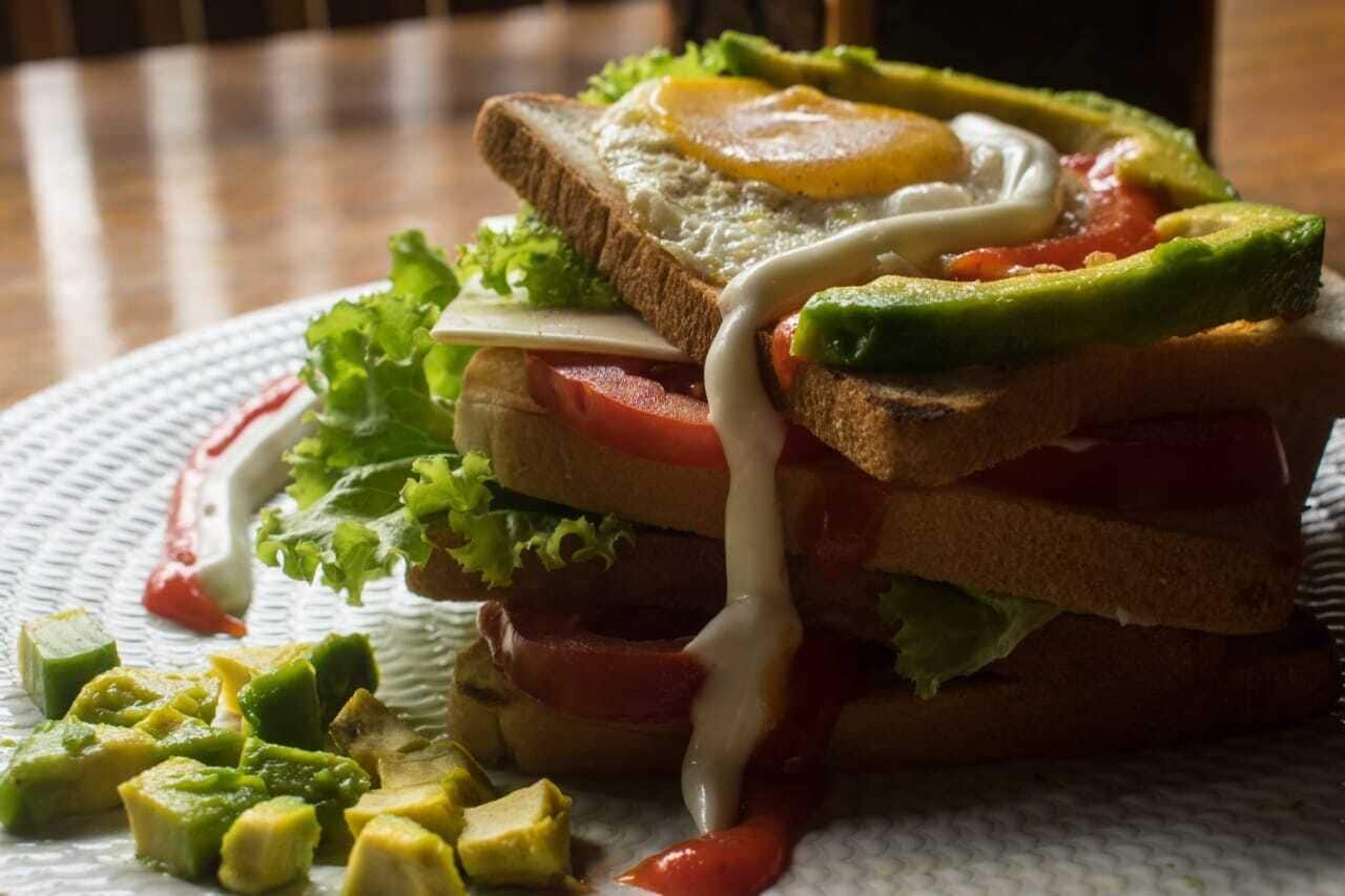 Un plat amb un entrepà i diferents ingredients i salsa.