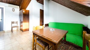 Ein Zimmer mit einem Holztisch, Stühlen, einem grünen Sofa und einem Holzschrank.