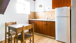 Eine kleine Küche mit Holdekor-Schränken, einem weißen Kühlschrank und einem Esstisch mit Stühlen.