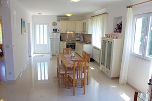A spacious kitchen with a dining area, featuring a large table, chairs, and modern appliances.