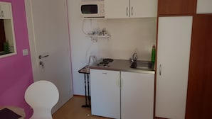A compact kitchen with white cabinets, a microwave, a sink, and a small table. - Guest House Avdic - Studio Apartment with Balcony (Dubrovnik)