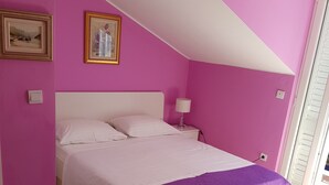 A bedroom with a bed, a nightstand, a lamp, a potted plant, and a white rug. - Guest House Avdic - Studio Apartment with Balcony (Dubrovnik)