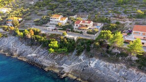 Zona residencial a la costa, amb cases construïdes sobre terreny rocos on s'albira el mar.