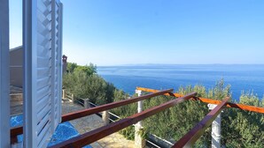 Un balcó amb vistes al mar, un camí de pedra i una porta blanca.