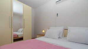 Un dormitori amb un llit, una tauleta de nit, una làmpada i un armari.