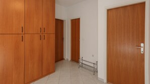 A hallway with wooden wardrobes, a metal rack, and a door with a handle. - Apartment Perina - Two Bedroom Apartment with Terrace and Sea View (Sutivan)