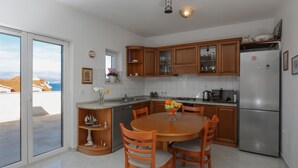 A modern kitchen with wooden cabinets, a stainless steel refrigerator, and a dining table with chairs. - Apartment Perina - Two Bedroom Apartment with Terrace and Sea View (Sutivan)