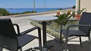 Un patio con dos sillas y una mesita, con vista a una carretera y al mar.