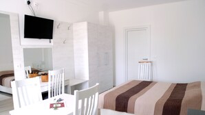 Un dormitorio con cama, escritorio, sillas, televisor y armario.
