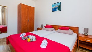 Une chambre d’hôtel avec un grand lit, deux tables de chevet, une armoire, un miroir et un tableau au mur.
