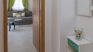 Ein Flur, der in einen Wohnbereich mit einem Sofa, einem kleinen Tisch und einer Kommode mit Spiegel führt.