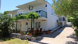 A two-story building with a balcony, outdoor seating area, and a sign that reads "APARTMANI". - Apartments Neven - One Bedroom Apartment with Terrace and Garden View (A2) (Drace)