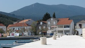 A coastal village with houses, a marina, and a mountain in the background. - Apartments Neven - One Bedroom Apartment with Terrace and Garden View (A2) (Drace)