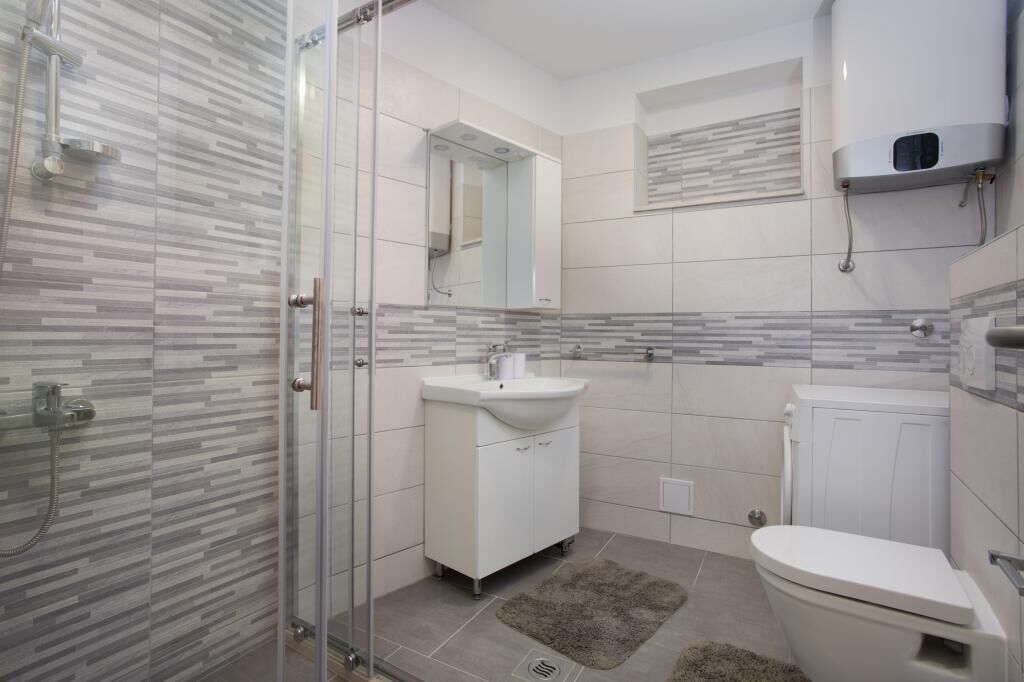Uma casa de banho moderna com cabine de duche de vidro, lavatório branco e sanita.