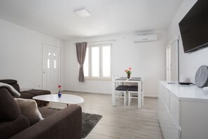Een moderne woonkamer met een bank, een kleine tafel en een eethoek met stoelen.