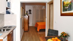Una cucina moderna con zona pranzo, inclusa una tavola con frutta e un vaso, e un letto sullo sfondo.