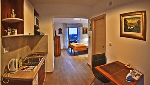 Una camera d'albergo compatta con angolo cottura, un letto con vista e un piccolo spazio pranzo.