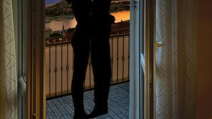 Silhouettes di una coppia su un balcone con vista sul tramonto.