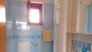 Une salle de bain avec des toilettes, un lavabo et une fenêtre.