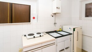 Une cuisine de taille réduite, équipée d’une cuisinière, d’un évier et d’un réfrigérateur.