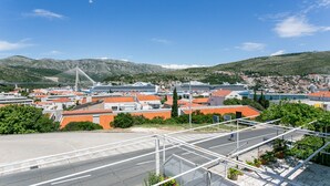 Un paysage urbain côtier avec un pont imposant, des navires de croisière amarrés et un mélange de bâtiments résidentiels et commerciaux.