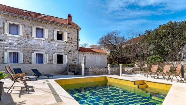 Un bâtiment en pierre doté d’une piscine, d’un espace extérieur aménagé et d’un mur en pierre.