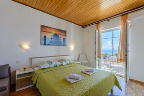 Une chambre à coucher comprenant un lit, des tables de chevet, une chaise et un tableau représentant une jetée.