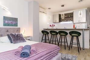 Ein modernes Hotelzimmer mit einem Bett, einer kleinen Küchenzeile und einer Bar mit Hockern.