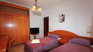 Una habitación de hotel con dos camas, un televisor, un armario de madera y un cuadro en la pared.