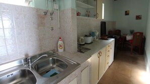 Una cocina con un lavamanos doble, un espejo, una encimera con varios electrodomésticos y un comedor con sillas y una mesa.