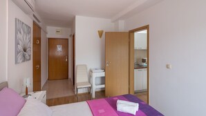 A hotel room with a bed, a desk, a chair, and a bathroom visible through an open door.