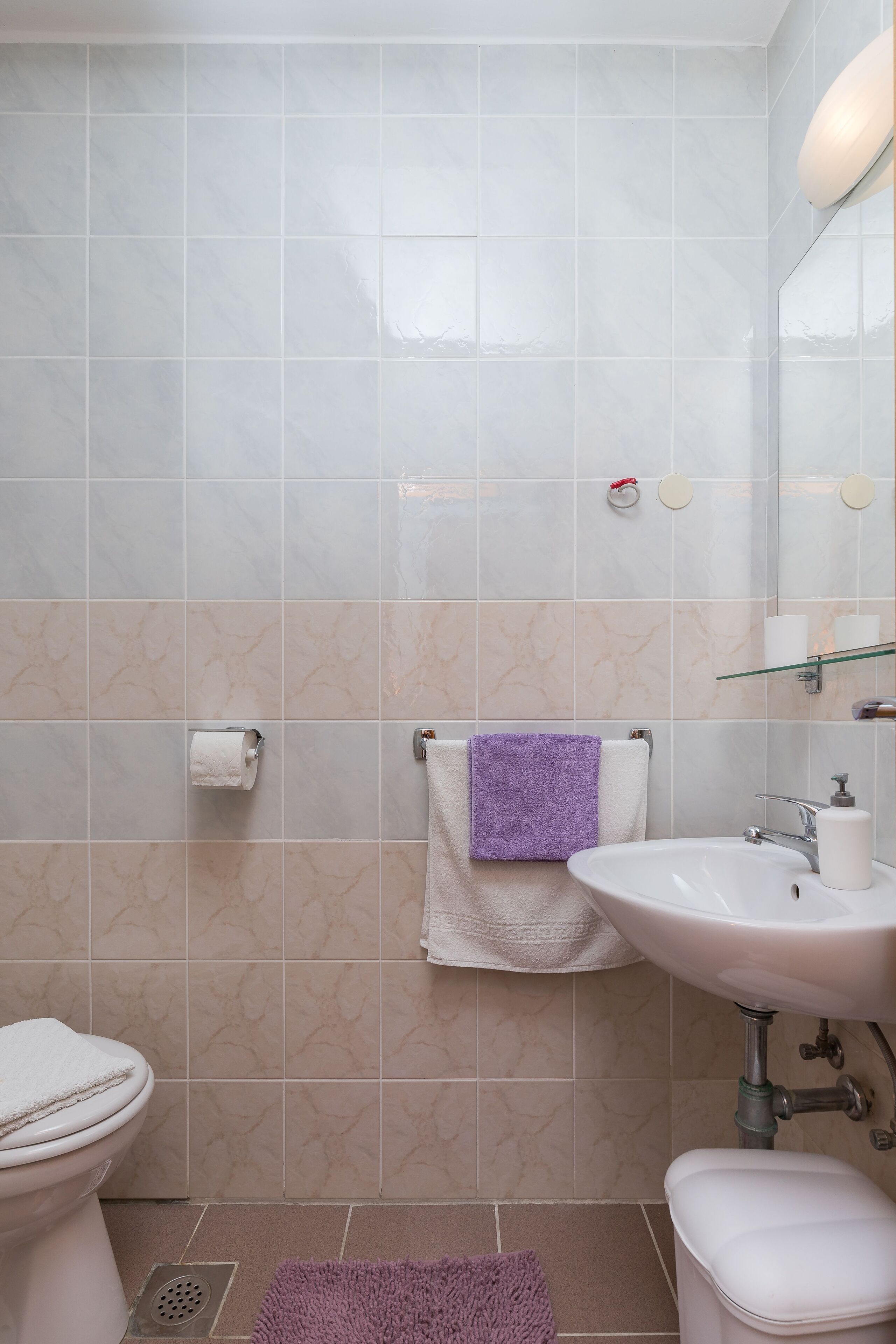 A bathroom with a toilet, sink, and a purple towel on a rack.