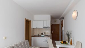 A compact living space with a kitchenette, a dining table, a sofa, and a small decorative vase.