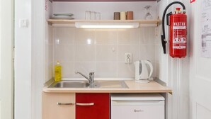 A compact kitchen with a dishwasher, a red cabinet, and a white trash bin. - Villa Iveta - Twin Room (Ground Floor) - Martina (Dubrovnik)