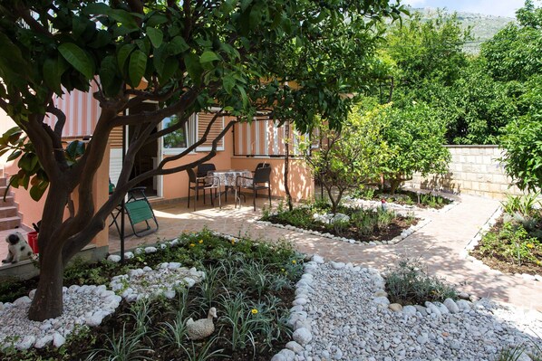 A garden with a patio area, stone pathway, and a small seating arrangement.
