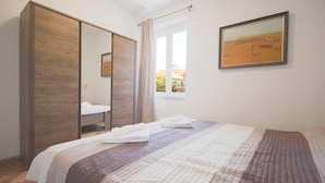 Une chambre avec un grand lit, une armoire, une fenêtre donnant sur un beau paysage et un tableau accroché au mur.