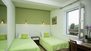 Ein Zimmer mit zwei Betten, einem Schreibtisch und einem Fenster mit Blick.