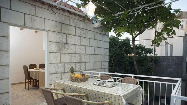 Eine Terrassengruppe mit Tisch und Stühlen, ein kleiner Garten und ein weißer Zaun.