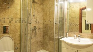 Ein Badezimmer mit Duschkabine, Toilette und Waschbecken mit Spiegel darüber.