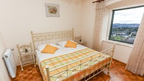 Una camera da letto con un letto, un termosifone, una finestra vista e un tavolino con una lampada.