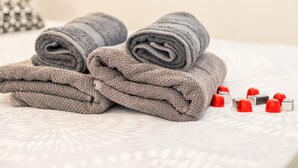 Neatly folded towels and red and silver bath accessories on a bed. - Guest House Nikolina - Double Room(2) (Dubrovnik)