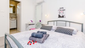 A modern hotel room with a neatly made bed, a bathroom with a sink and mirror, and a wall-mounted air conditioner. - Guest House Nikolina - Double Room(2) (Dubrovnik)