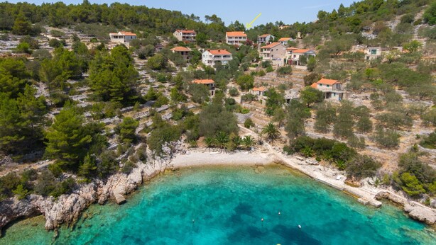 An aerial view of a coastal village with houses built on a hillside overlooking a clear turquoise sea. - Holiday Home Diana - Comfort Two Bedroom Apartment with Terrace and Sea View (Vela Luka)