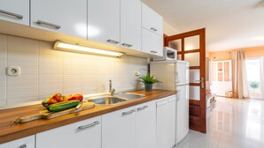 A modern kitchen with white cabinets, a wooden countertop, a sink, and a microwave. - Holiday Home Diana - Comfort Two Bedroom Apartment with Terrace and Sea View (Vela Luka)