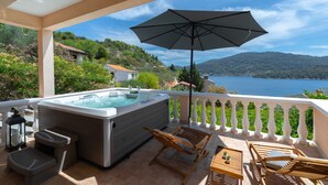A balcony with a hot tub, wooden chairs, a table, and an umbrella. - Holiday Home Diana - Comfort Two Bedroom Apartment with Terrace and Sea View (Vela Luka)