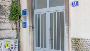 A building entrance with a grey double door, a small sign with the number 11, and a utility box with stickers. - Old City Center Suite - One Bedroom Suite (Split)